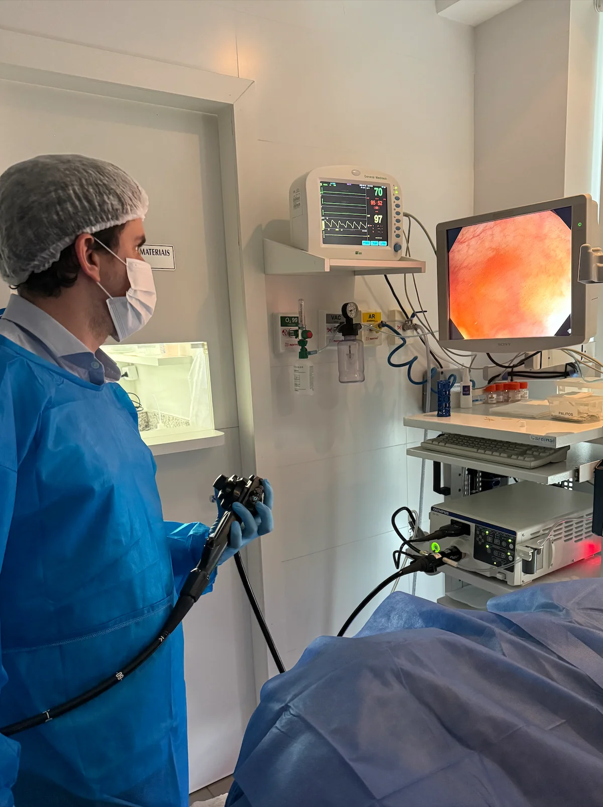Dr. Matheus Massahud realizando colonoscopia, com a imagem do intestino exibida no monitor.